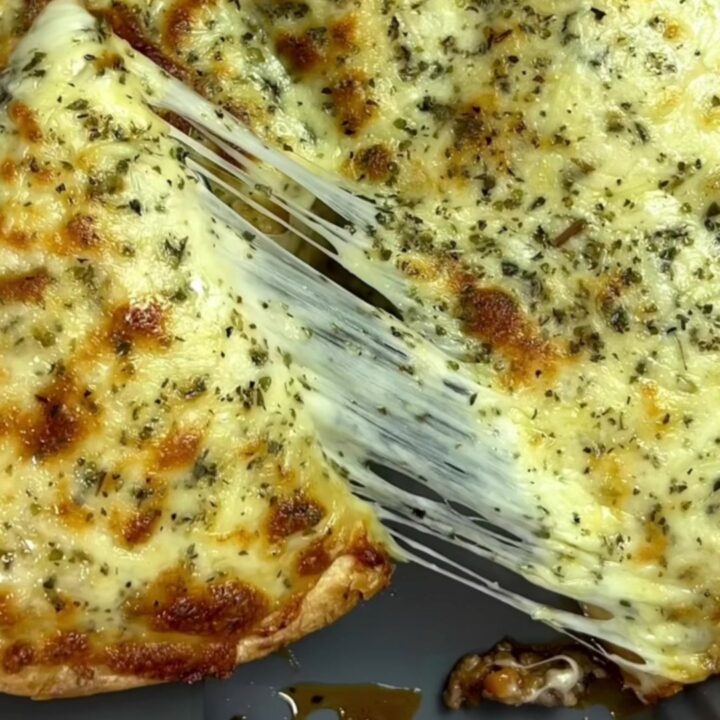 Golden brown tortilla pockets topped with melted mozzarella and fresh parsley, served on a wooden board.