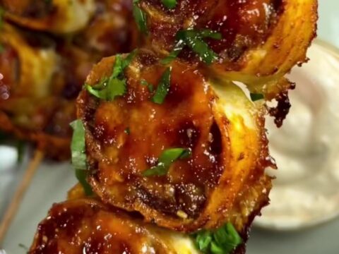Skewer of glazed beef tortilla wheels with melted cheese and scallions