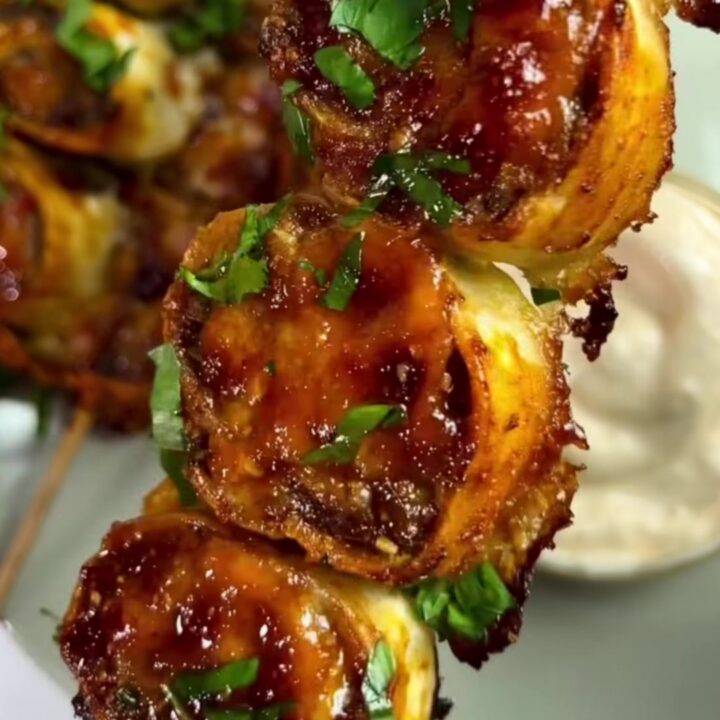 Skewer of glazed beef tortilla wheels with melted cheese and scallions