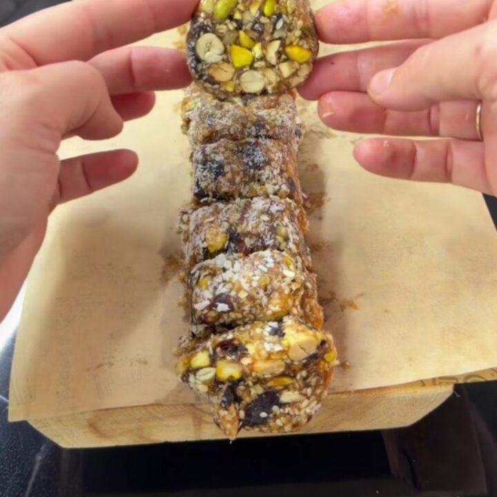 A stack of date and nut bars coated in coconut flakes on a parchment-lined tray.
