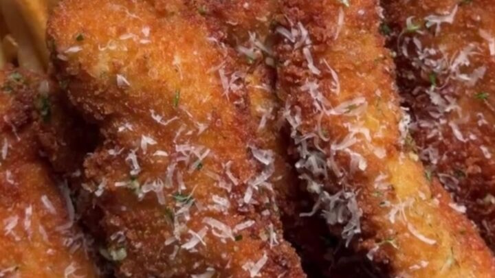 Golden crispy chicken tenders piled on butcher paper with a ramekin of creamy orange dip and fresh parsley