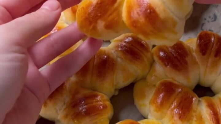 Golden flower-shaped brioche buns with sesame and nigella seeds on a baking sheet