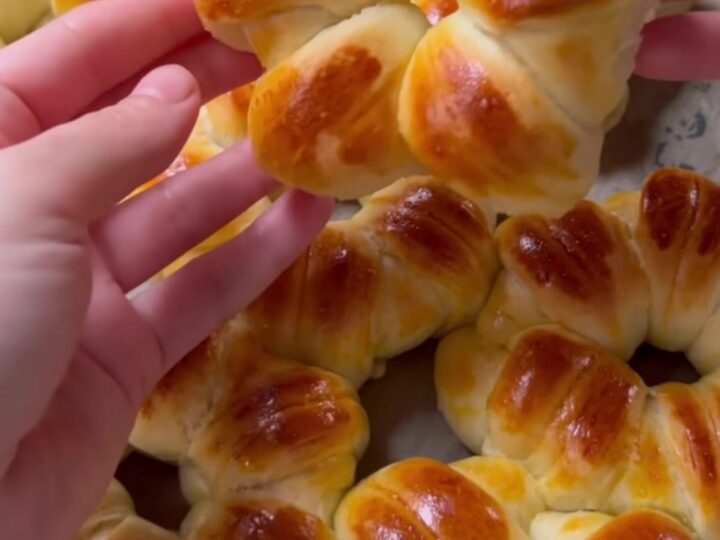 Golden flower-shaped brioche buns with sesame and nigella seeds on a baking sheet