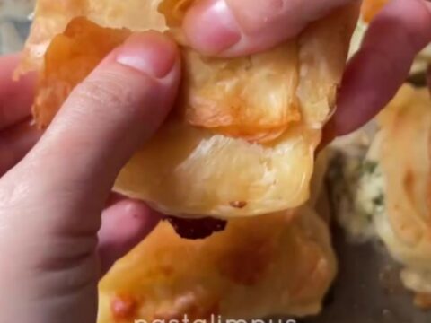 Golden spiral Turkish börek with crispy layers and beef filling on a round tray