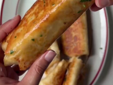 Golden baked chicken roll-ups with parmesan crust and melted cheese on a cutting board