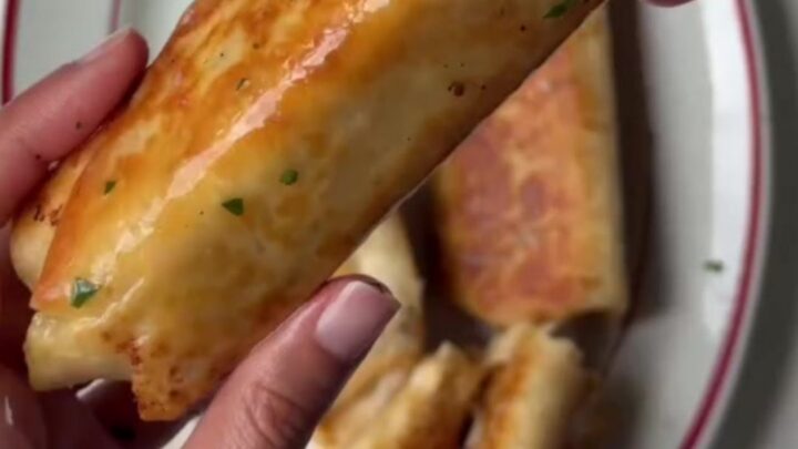 Golden baked chicken roll-ups with parmesan crust and melted cheese on a cutting board