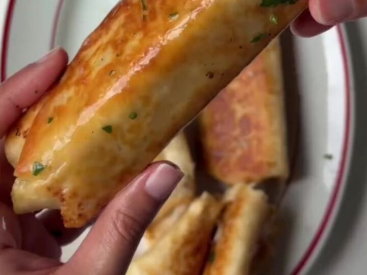 Golden baked chicken roll-ups with parmesan crust and melted cheese on a cutting board