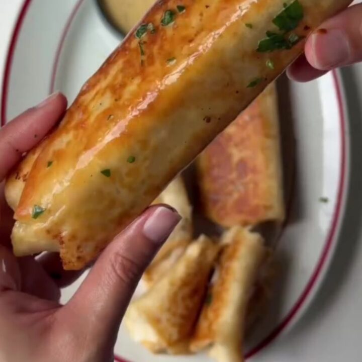 Golden baked chicken roll-ups with parmesan crust and melted cheese on a cutting board