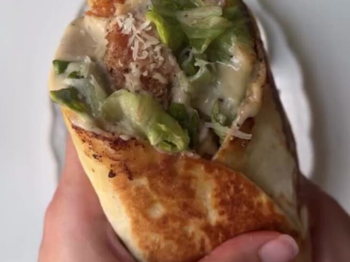 Crispy chicken Caesar wrap cut in half showing golden chicken, romaine, and parmesan