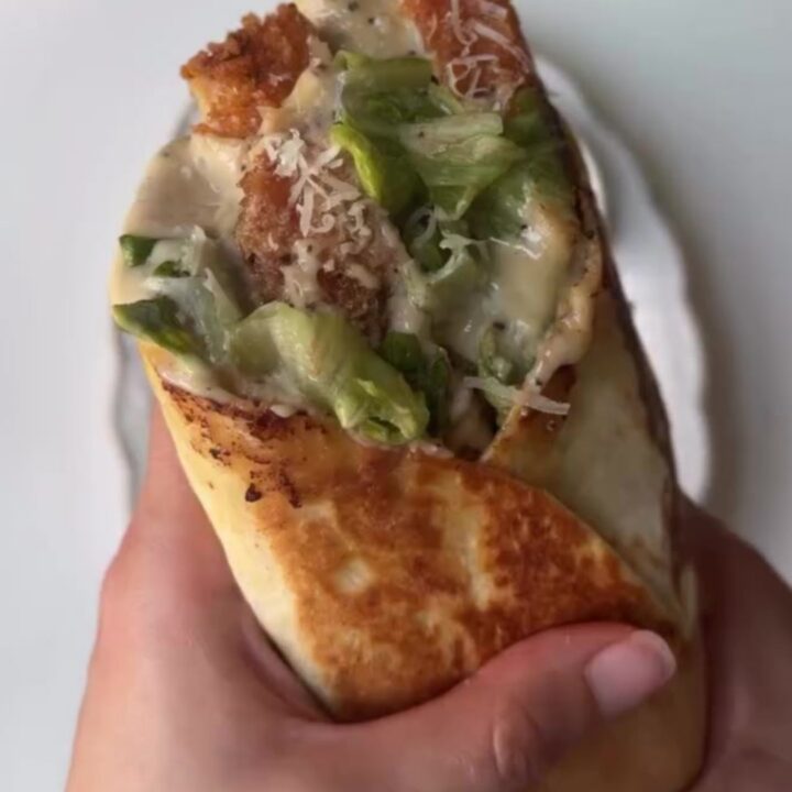 Crispy chicken Caesar wrap cut in half showing golden chicken, romaine, and parmesan