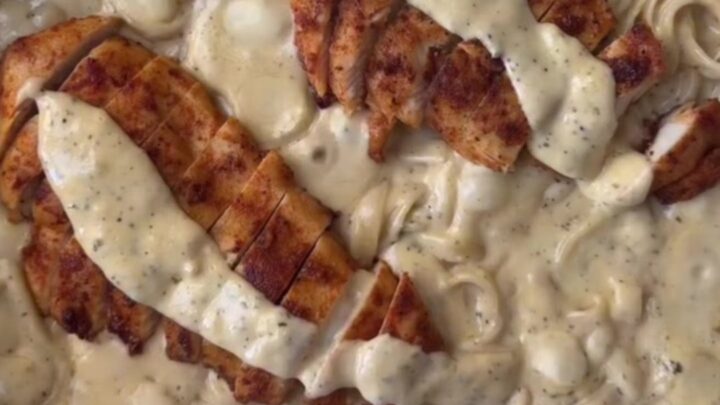A plate of lemon garlic chicken Alfredo with sliced chicken and parsley on top