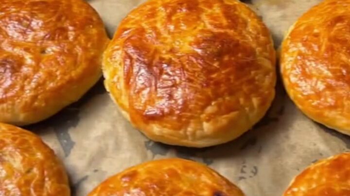 Golden coiled Turkish börek on a baking sheet, crust glistening with butter, spiral visible