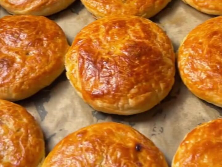 Golden coiled Turkish börek on a baking sheet, crust glistening with butter, spiral visible