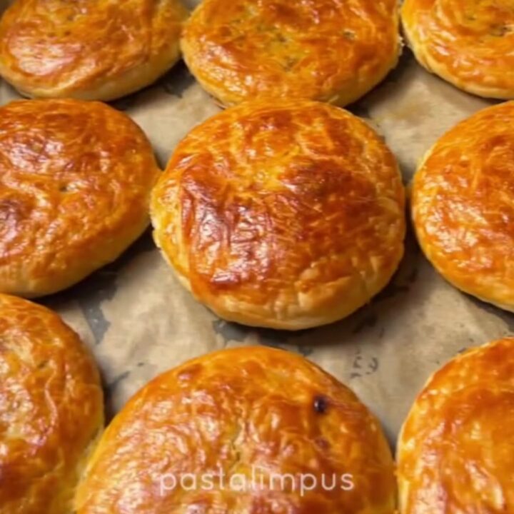 Golden coiled Turkish börek on a baking sheet, crust glistening with butter, spiral visible