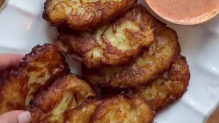 Golden crispy garlic parmesan hashbrowns stacked on a plate with a bowl of spicy mayo for dipping.