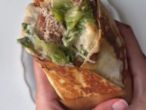 Golden crispy chicken Caesar wrap sliced in half, showing crunchy romaine and chicken