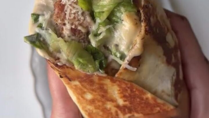 Golden crispy chicken Caesar wrap sliced in half, showing crunchy romaine and chicken