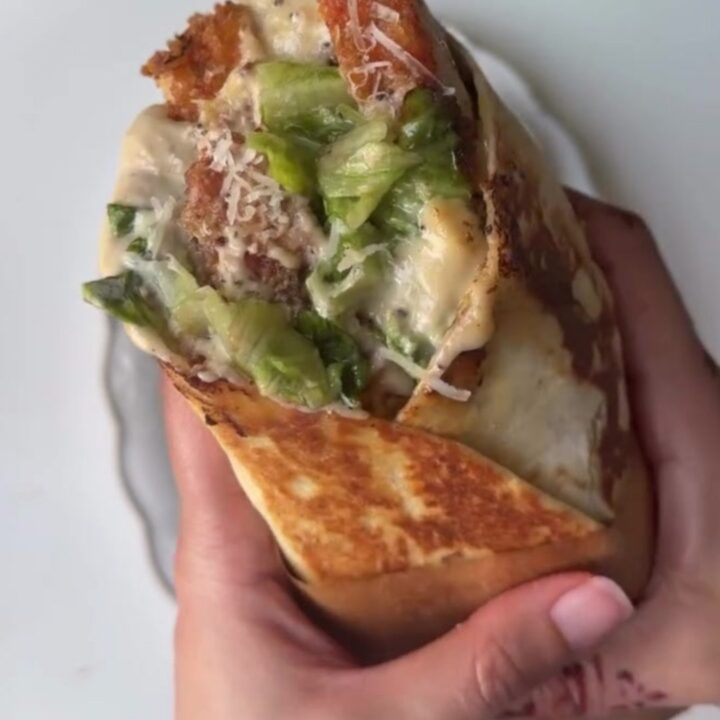 Golden crispy chicken Caesar wrap sliced in half, showing crunchy romaine and chicken