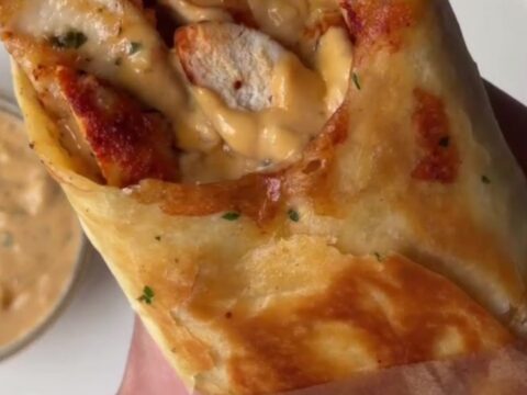 Crispy chicken Alfredo wrap sliced in half, showing creamy filling and melted cheese