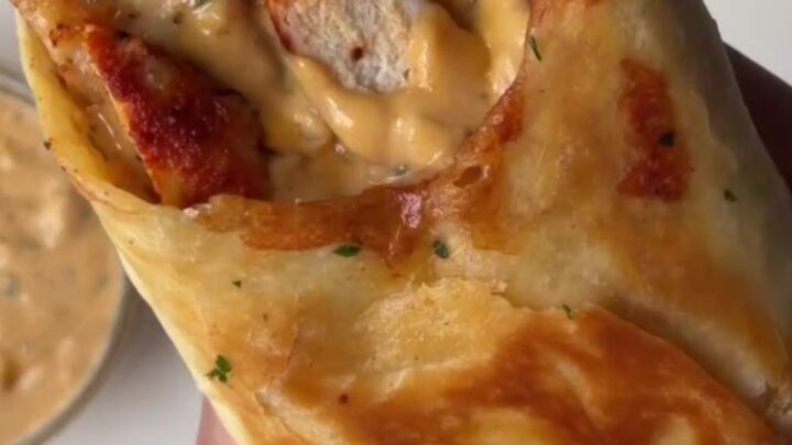 Crispy chicken Alfredo wrap sliced in half, showing creamy filling and melted cheese