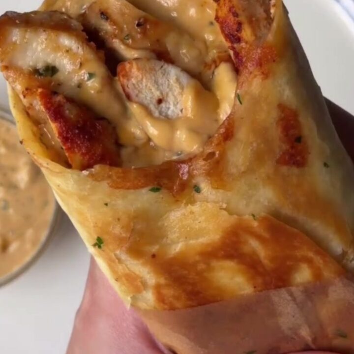 Crispy chicken Alfredo wrap sliced in half, showing creamy filling and melted cheese