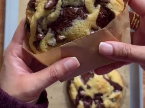 A stack of golden cookies with crispy edges and gooey chocolate centers, sprinkled with flaky sea salt.