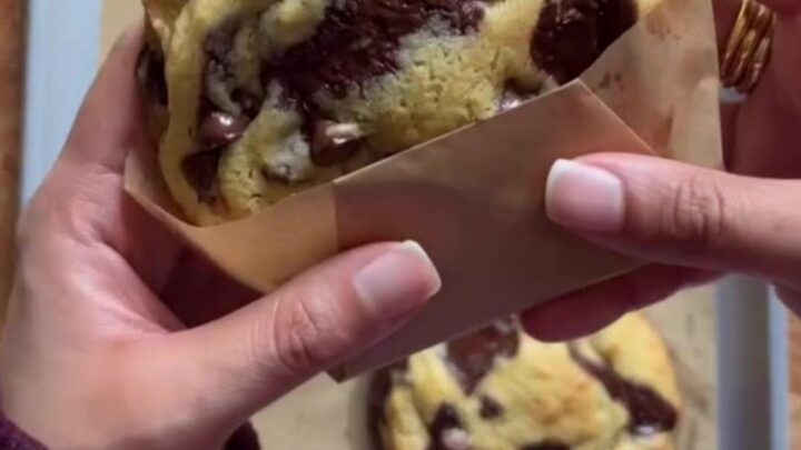 A stack of golden cookies with crispy edges and gooey chocolate centers, sprinkled with flaky sea salt.