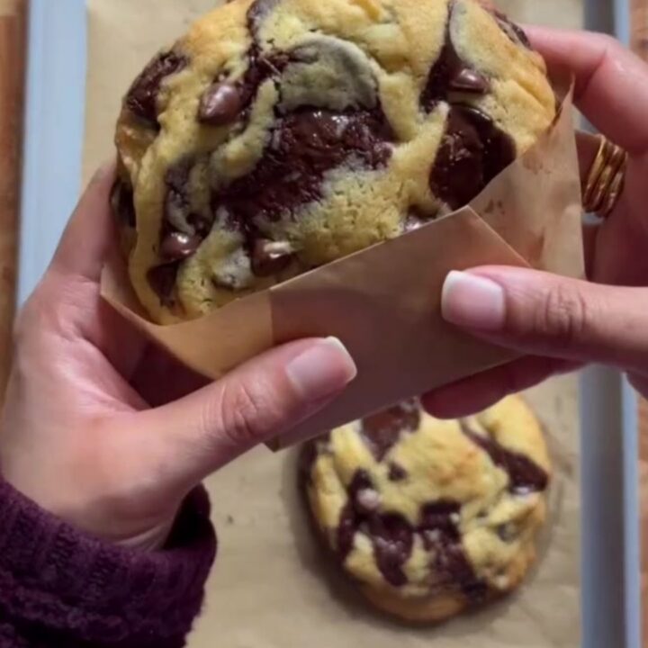 A stack of golden cookies with crispy edges and gooey chocolate centers, sprinkled with flaky sea salt.