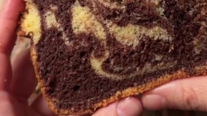 A golden marble loaf cake dusted with powdered sugar, showing a zebra swirl inside.