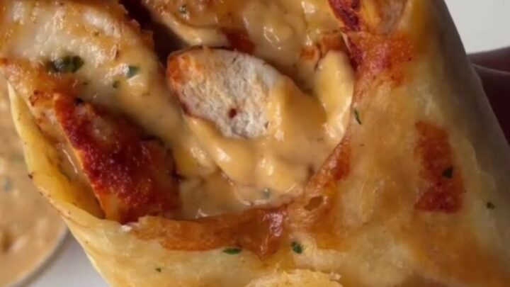Crispy chicken Alfredo wrap cut in half, showing creamy sauce and melted cheese.