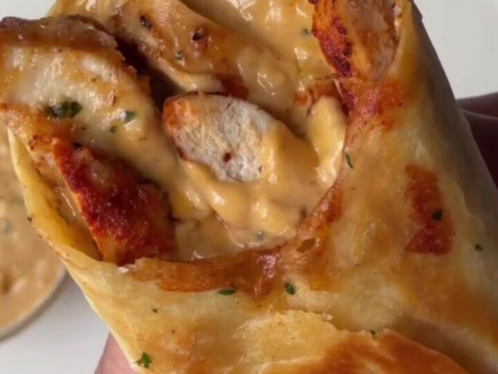 Crispy chicken Alfredo wrap cut in half, showing creamy sauce and melted cheese.