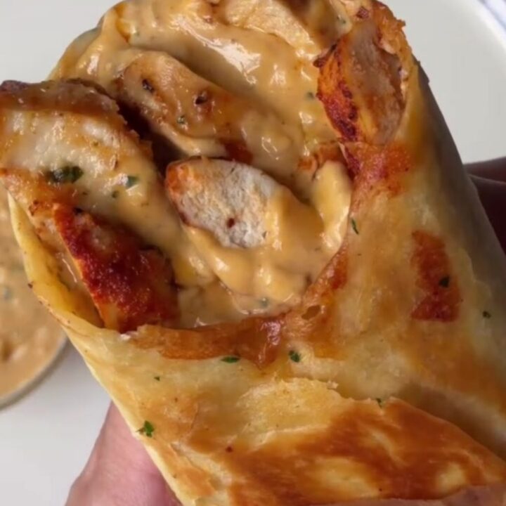 Crispy chicken Alfredo wrap cut in half, showing creamy sauce and melted cheese.