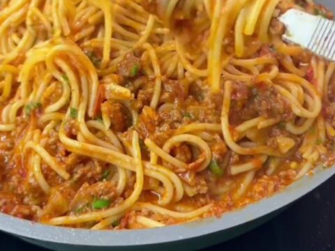 Baked rigatoni with meatballs and a blistered mozzarella crust, garnished with fresh basil