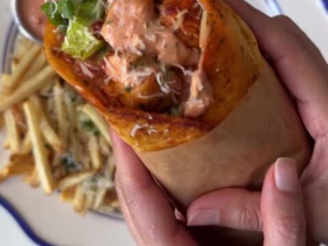 Crispy garlic parmesan chicken wrap cut diagonally, showing melted mozzarella and chicken, with garlic mayo dip
