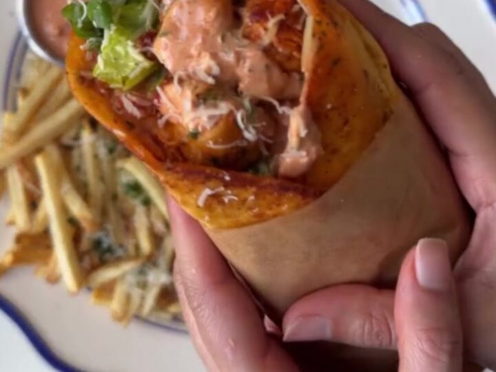 Crispy garlic parmesan chicken wrap cut diagonally, showing melted mozzarella and chicken, with garlic mayo dip