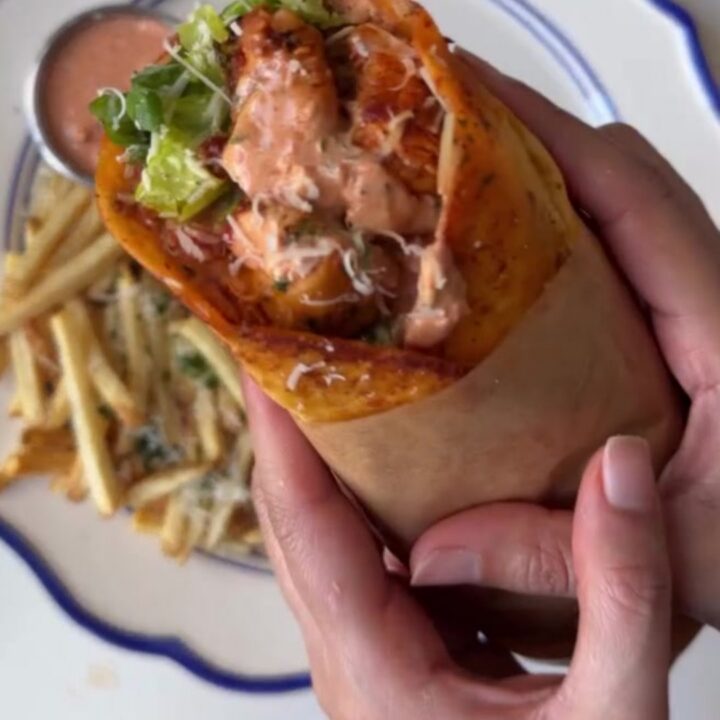 Crispy garlic parmesan chicken wrap cut diagonally, showing melted mozzarella and chicken, with garlic mayo dip