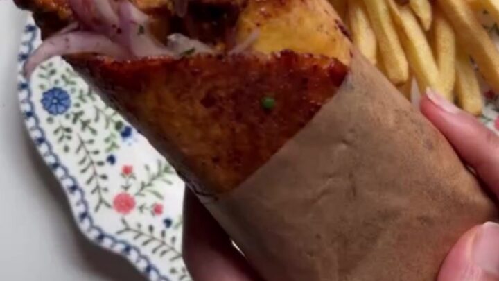 Crispy chicken shawarma wrap cut in half, showing layers of chicken, toum, fries, and pickled turnips