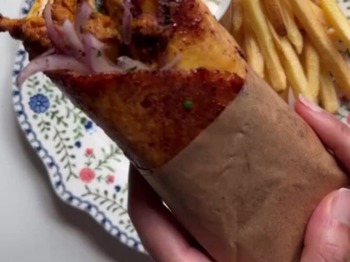 Crispy chicken shawarma wrap cut in half, showing layers of chicken, toum, fries, and pickled turnips