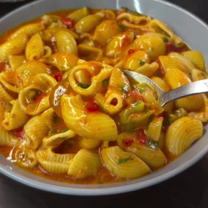 Baked feta shell pasta in a baking dish, creamy pink sauce coating shells, garnished with basil and parmesan.