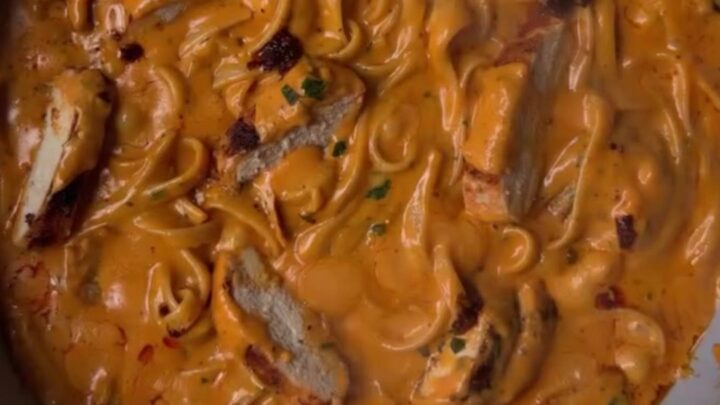Spicy chicken Alfredo fettuccine with chili crisp and scallions in a white bowl
