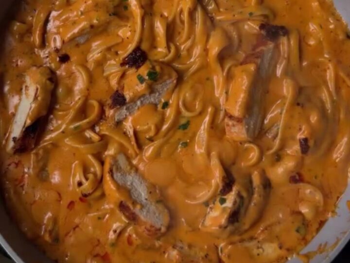 Spicy chicken Alfredo fettuccine with chili crisp and scallions in a white bowl