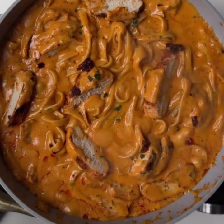 Spicy chicken Alfredo fettuccine with chili crisp and scallions in a white bowl