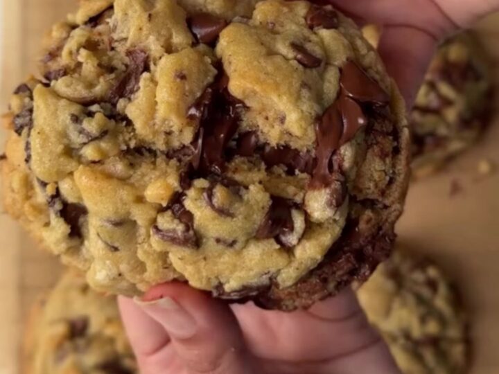 Gooey chocolate chip cookie broken in half with melted chocolate pulling