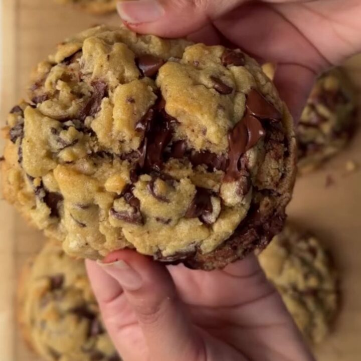 Gooey chocolate chip cookie broken in half with melted chocolate pulling