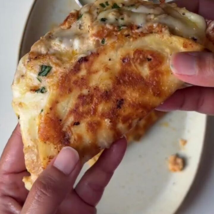 Crispy chicken Alfredo tacos on a plate with warm Alfredo dipping sauce and fresh parsley garnish.