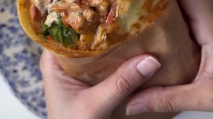 Crispy chipotle chicken wrap sliced diagonally, showing melted cheese and juicy chicken.