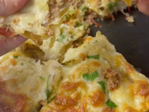 Golden tortilla pie with bubbling cheese and garlic butter, cut into a wedge with cheese stretching.