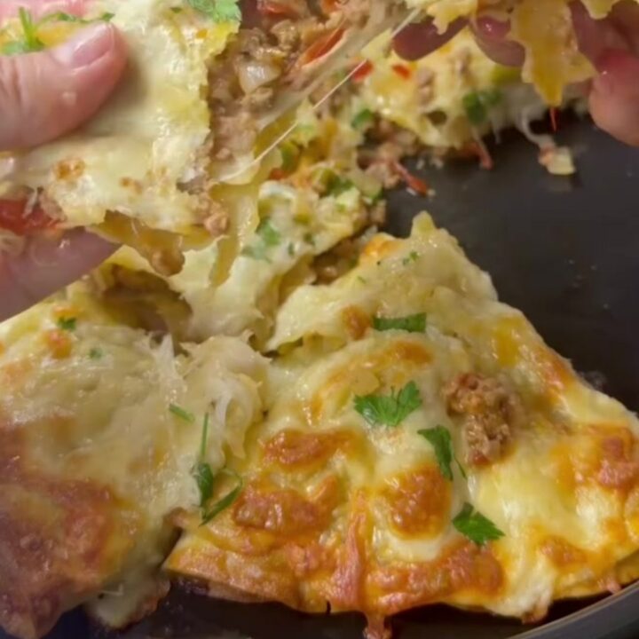 Golden tortilla pie with bubbling cheese and garlic butter, cut into a wedge with cheese stretching.
