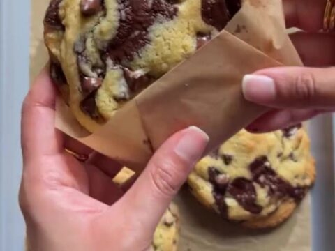 Tall, craggy chocolate chip cookie broken open showing molten chocolate center