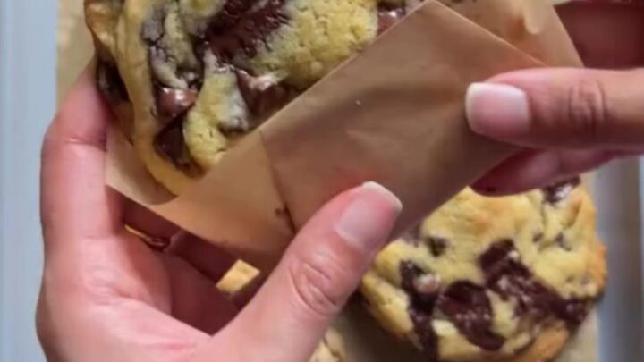 Tall, craggy chocolate chip cookie broken open showing molten chocolate center